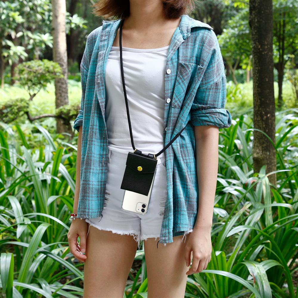 Donna con camicia blu, pantaloncini bianchi e custodia nera in un parco verde.