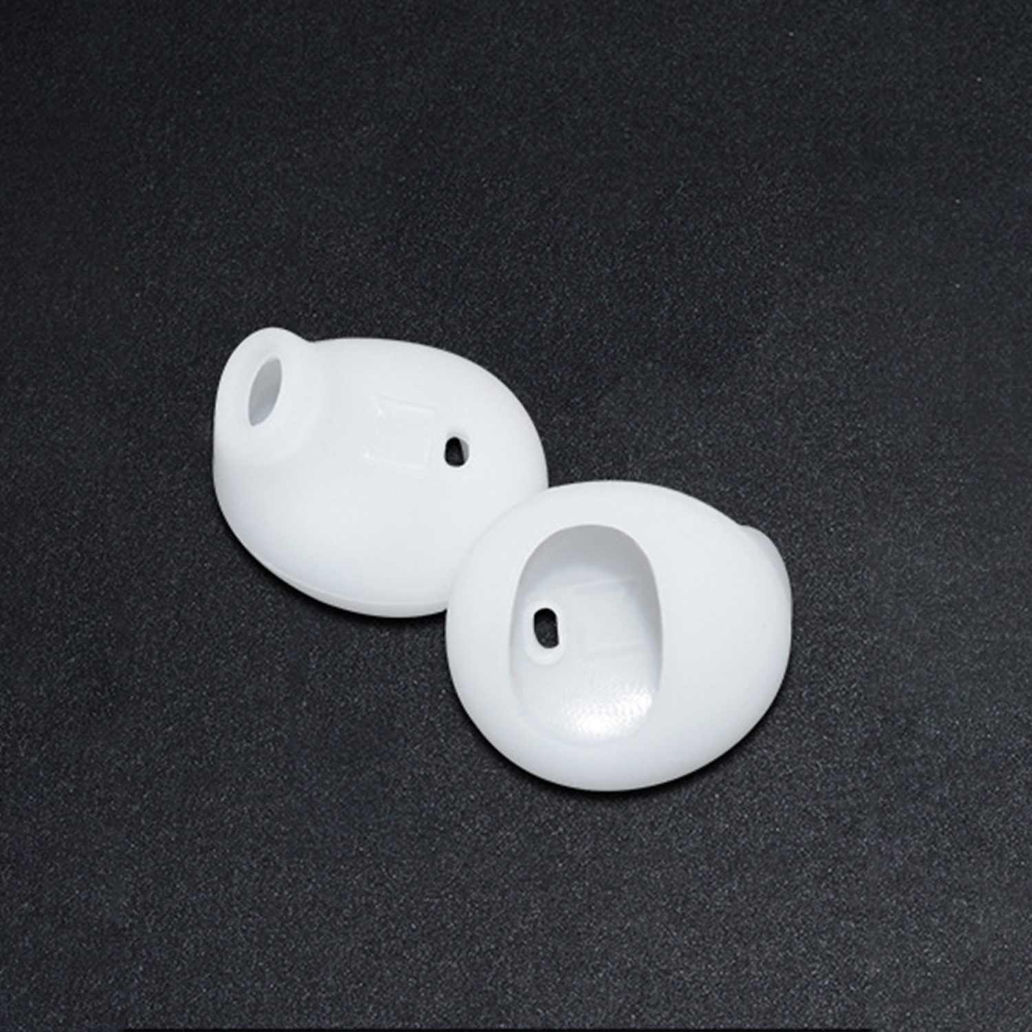 Witte oortips. Twee stuks op een zwart oppervlak. Close-up.