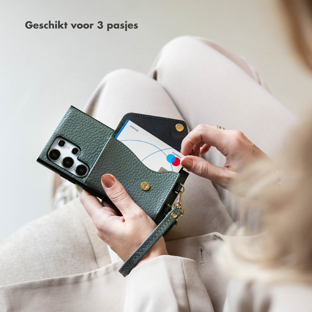 Een persoon die een telefoonhoesje in portemonnee-stijl vasthoudt met kaarten erin.
