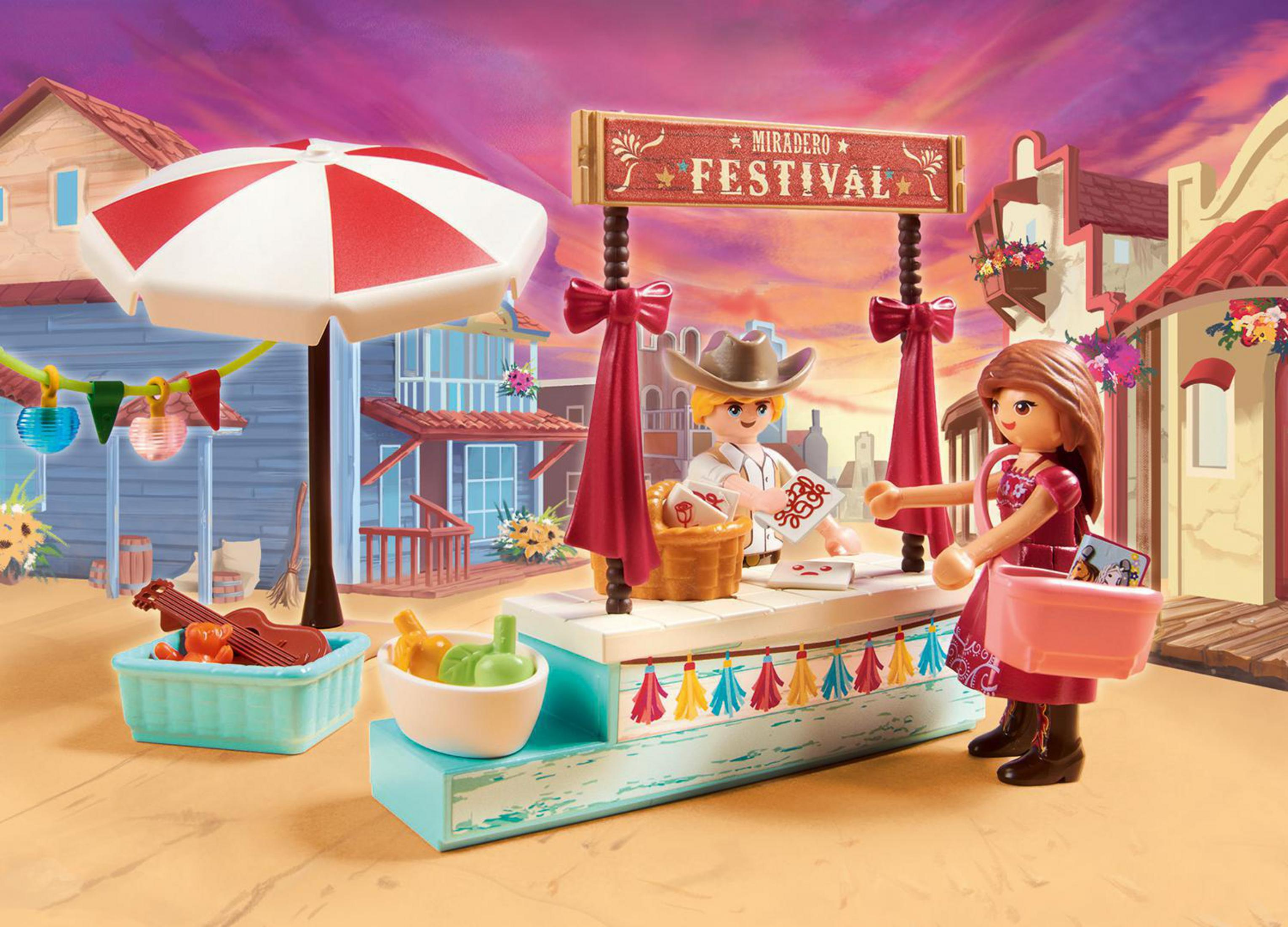 Escena de Playmobil: Dos figuras en un puesto de festival. Entorno colorido con edificios, accesorios y decoraciones.