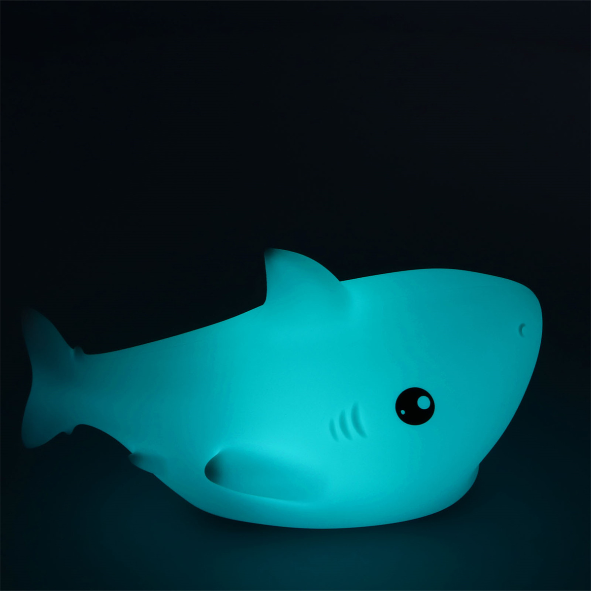 Ein blaues hai-förmiges Nachtlicht, das auf dunklem Hintergrund leuchtet.