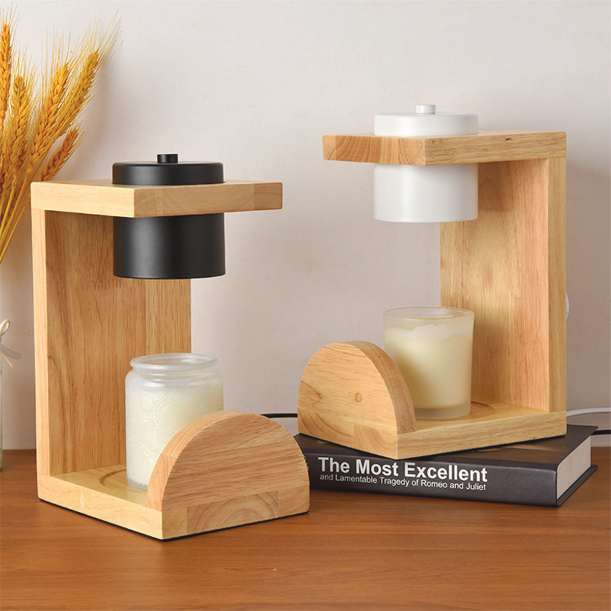 Zwei Kerzenhalter aus Holz mit Kerzen und einem Buch auf einem Tisch. Einer ist schwarz, einer ist weiß.