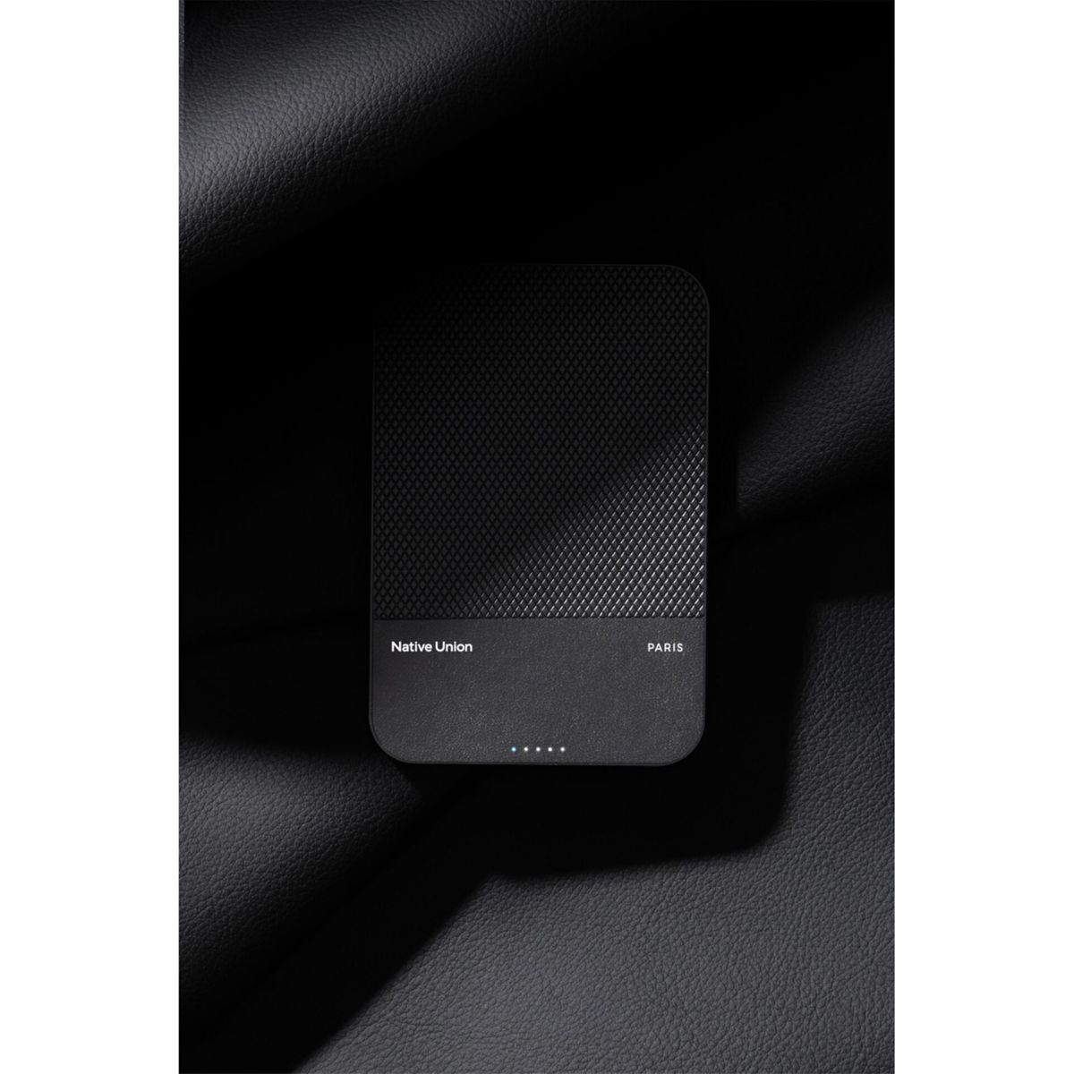 Chargeur sans fil noir avec surface texturée, sur fond simili cuir.