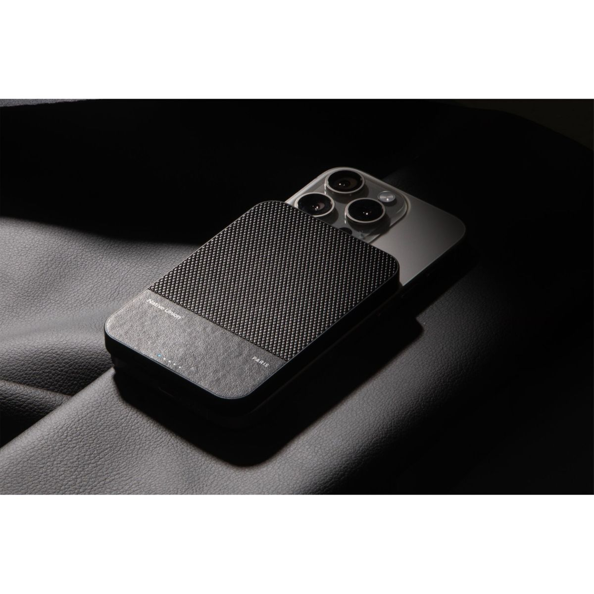 Chargeur portable noir sur un téléphone, sur une surface en cuir sombre, gros plan.