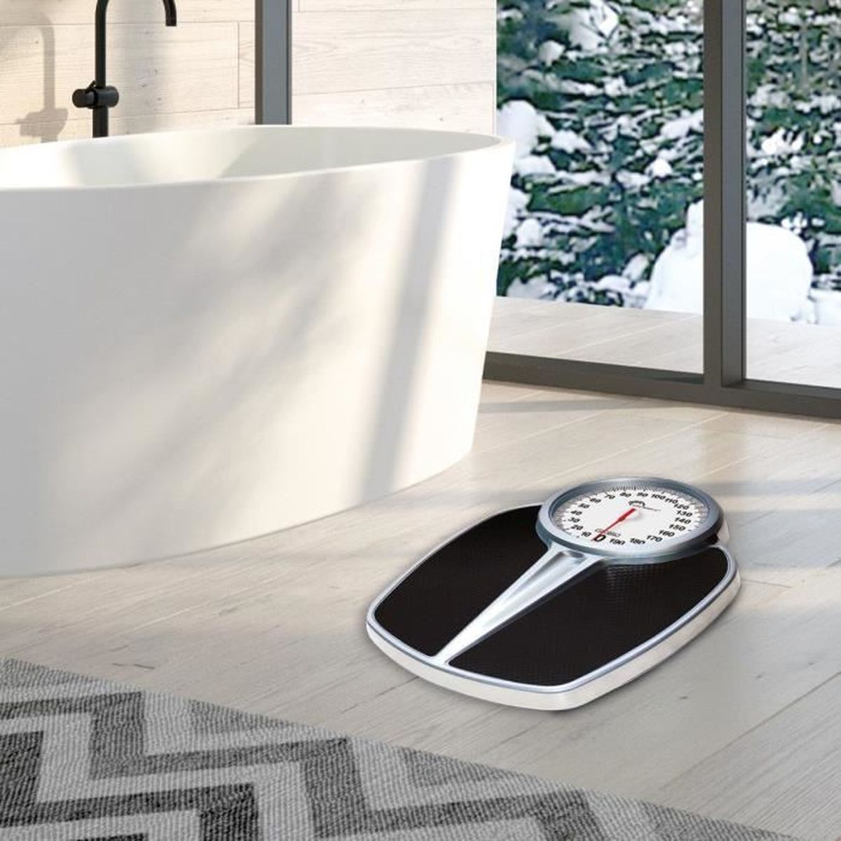 Badezimmer mit Waage vor Badewanne und Fenster mit Schneeblick.