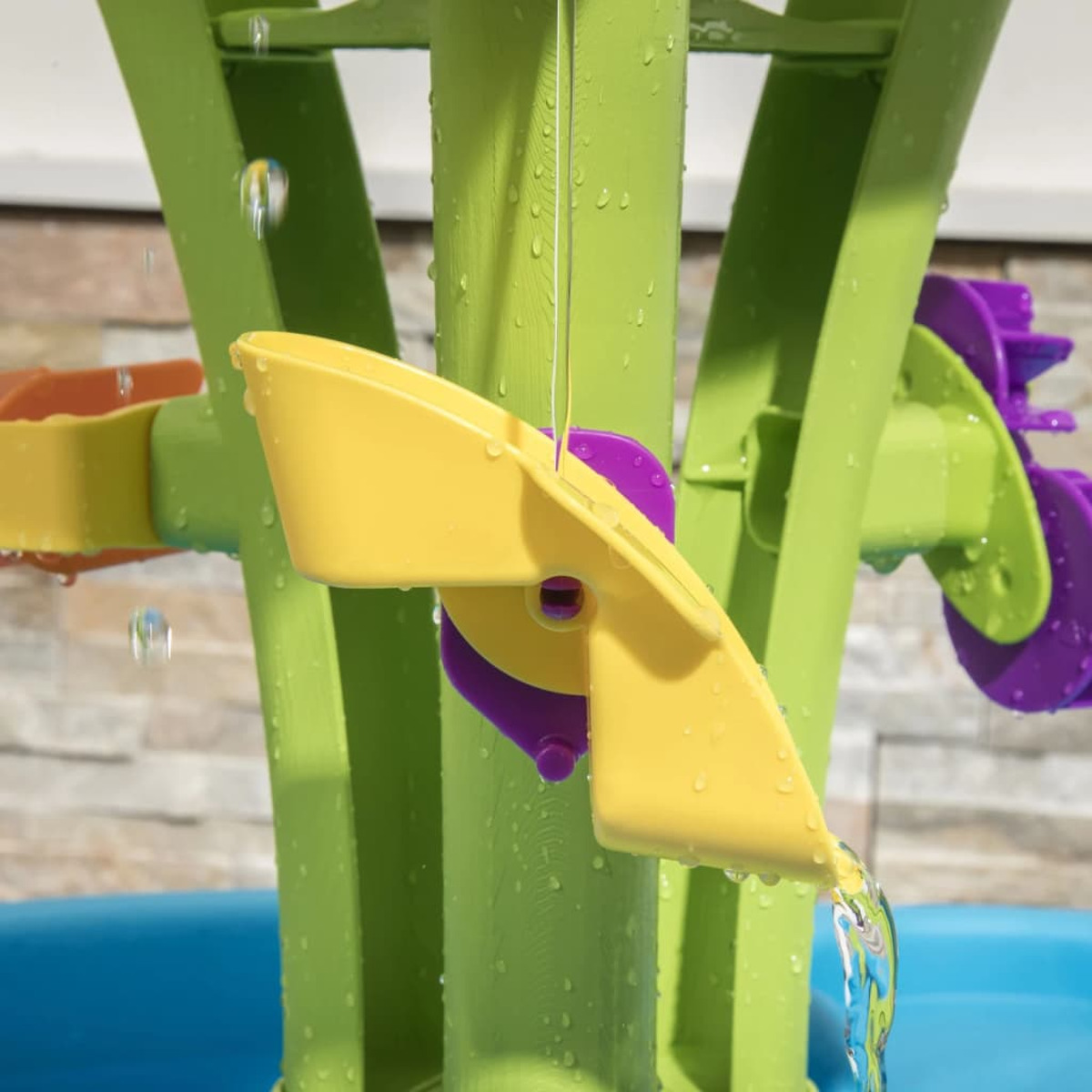 Nahaufnahme eines grünen und gelben Wasserspielzeugs. Wasser fließt aus einem gelben Ausguss.