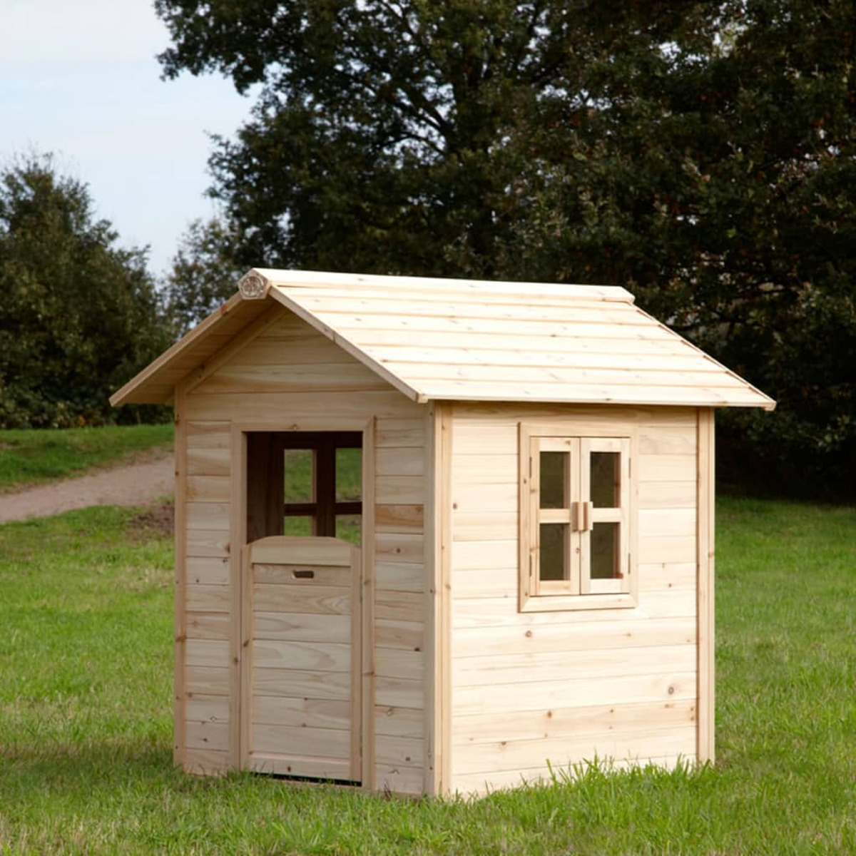 Ein Spielhaus aus Holz steht auf Gras. Es hat eine Tür, Fenster und ein Satteldach.