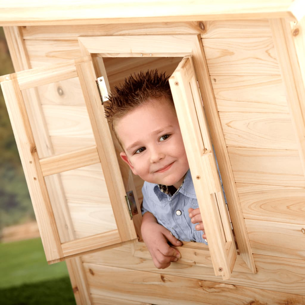 Ein Kind, das aus einem Fenster eines Holzspielhauses herauslugt und lächelt.