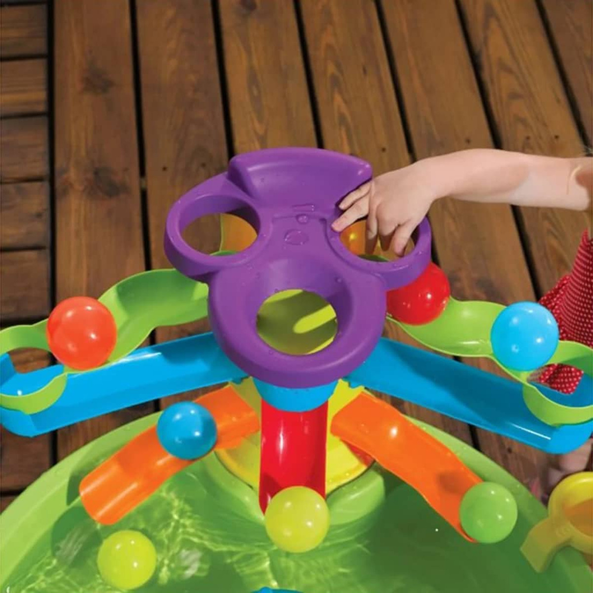 Kinderhand interagiert mit bunten Wassertischspielzeug mit Bällen.