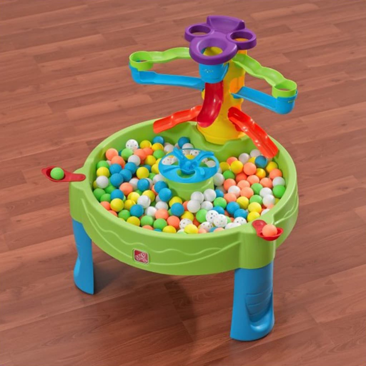 Ein farbenfroher Kinderspieltisch mit Bällen. Zu den Merkmalen gehören Rutschen und ein Drehrad.