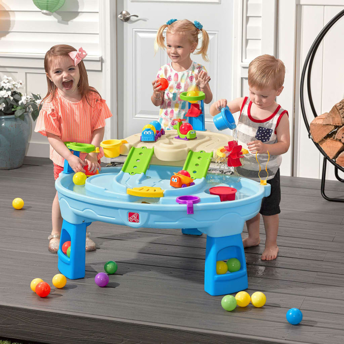 Drei Kinder spielen mit einem blauen Step2-Wassertisch mit verschiedenen Spielzeugen und Bällen.
