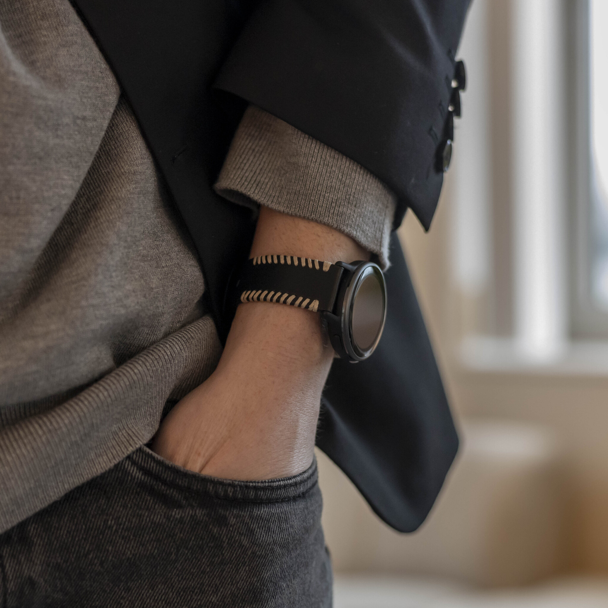 Handgelenk einer Person mit Smartwatch und schwarzer Jacke.