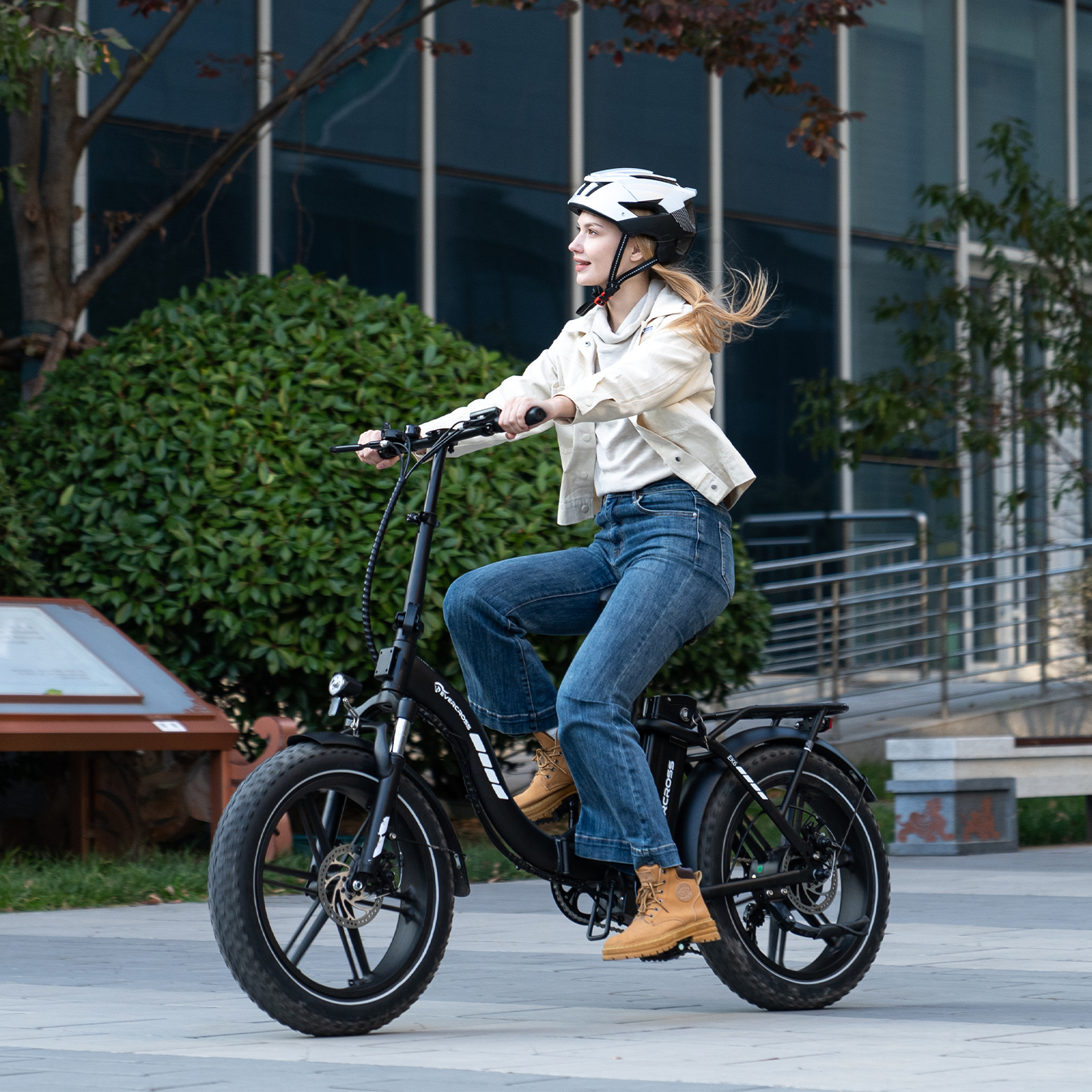 Eine Frau mit Helm fährt mit einem schwarzen E-Bike auf einem asphaltierten Weg.
