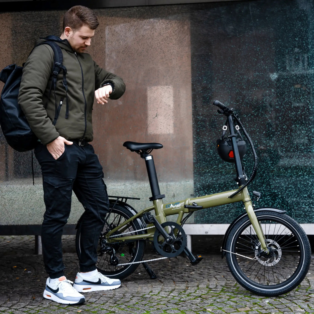 Ein Mann neben einem grünen Fahrrad, der auf seine Smartwatch blickt, in der Nähe einer Glaswand.
