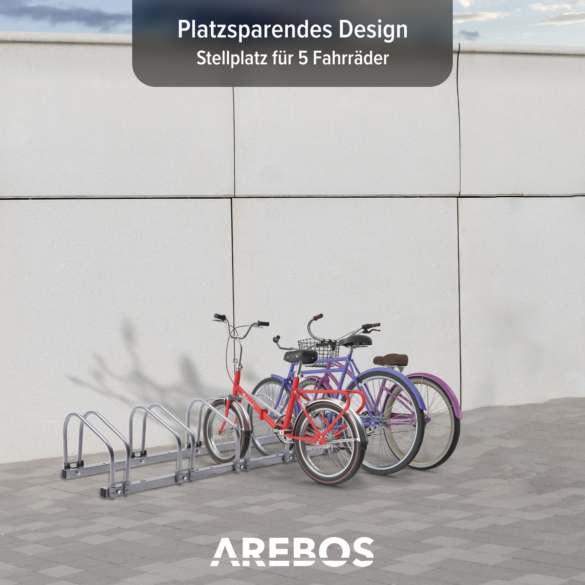 Fahrräder auf einem Metallgestell geparkt. Das Gestell steht in der Nähe einer weißen Wand. Drei Fahrräder sind sichtbar.