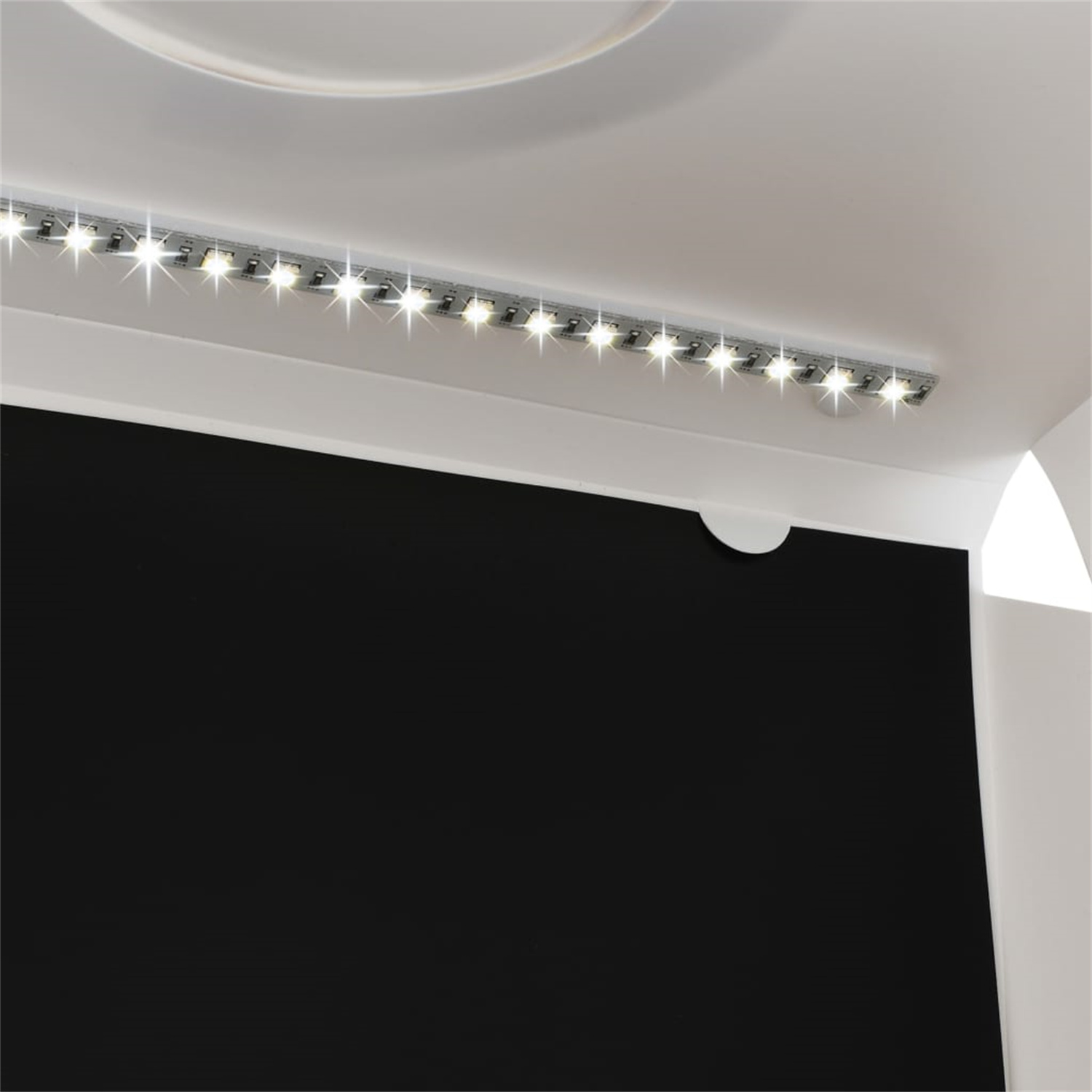 Eine Decke mit weißem Sockel und einer schwarzen Platte. Eine Reihe von LED-Leuchten befindet sich an der Decke.