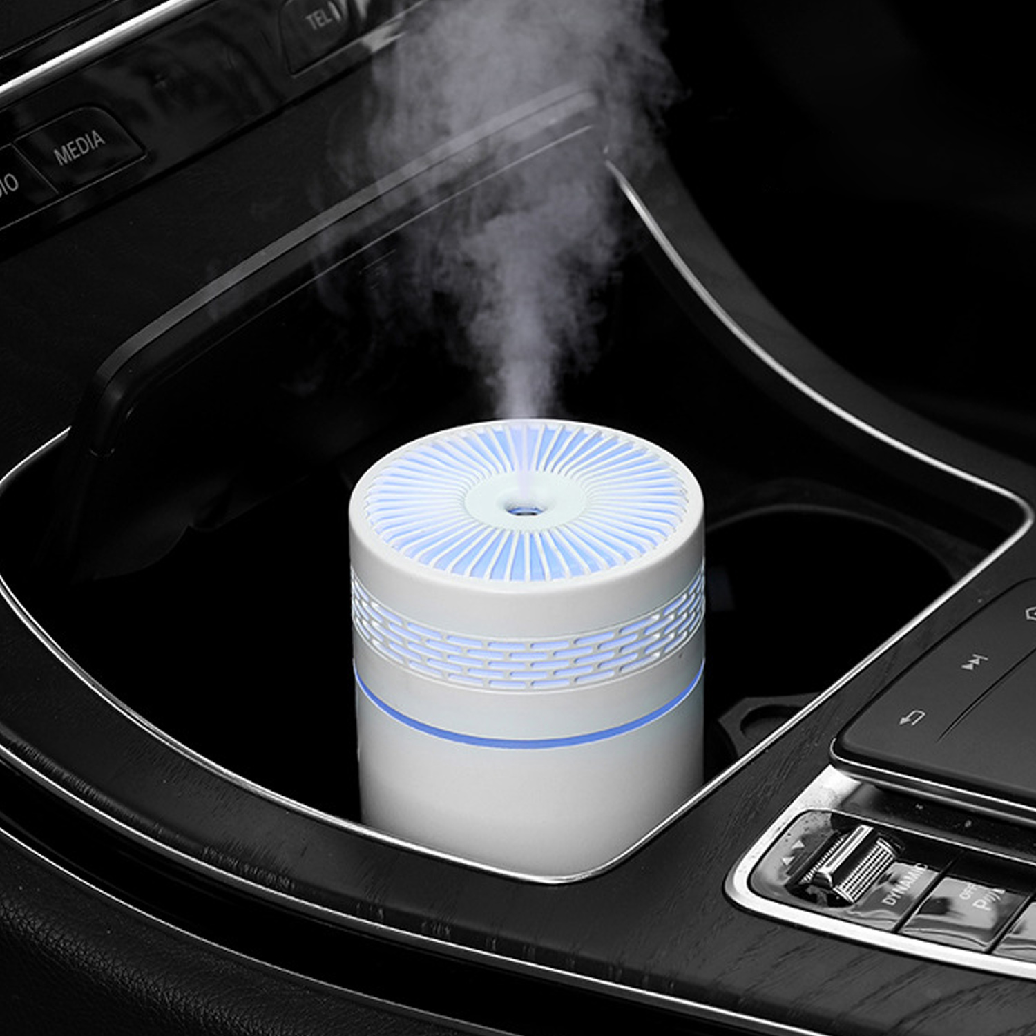 Biało-niebieski nawilżacz powietrza do samochodu. Jest w uchwycie na kubek w samochodzie. Para wydobywa się z góry.