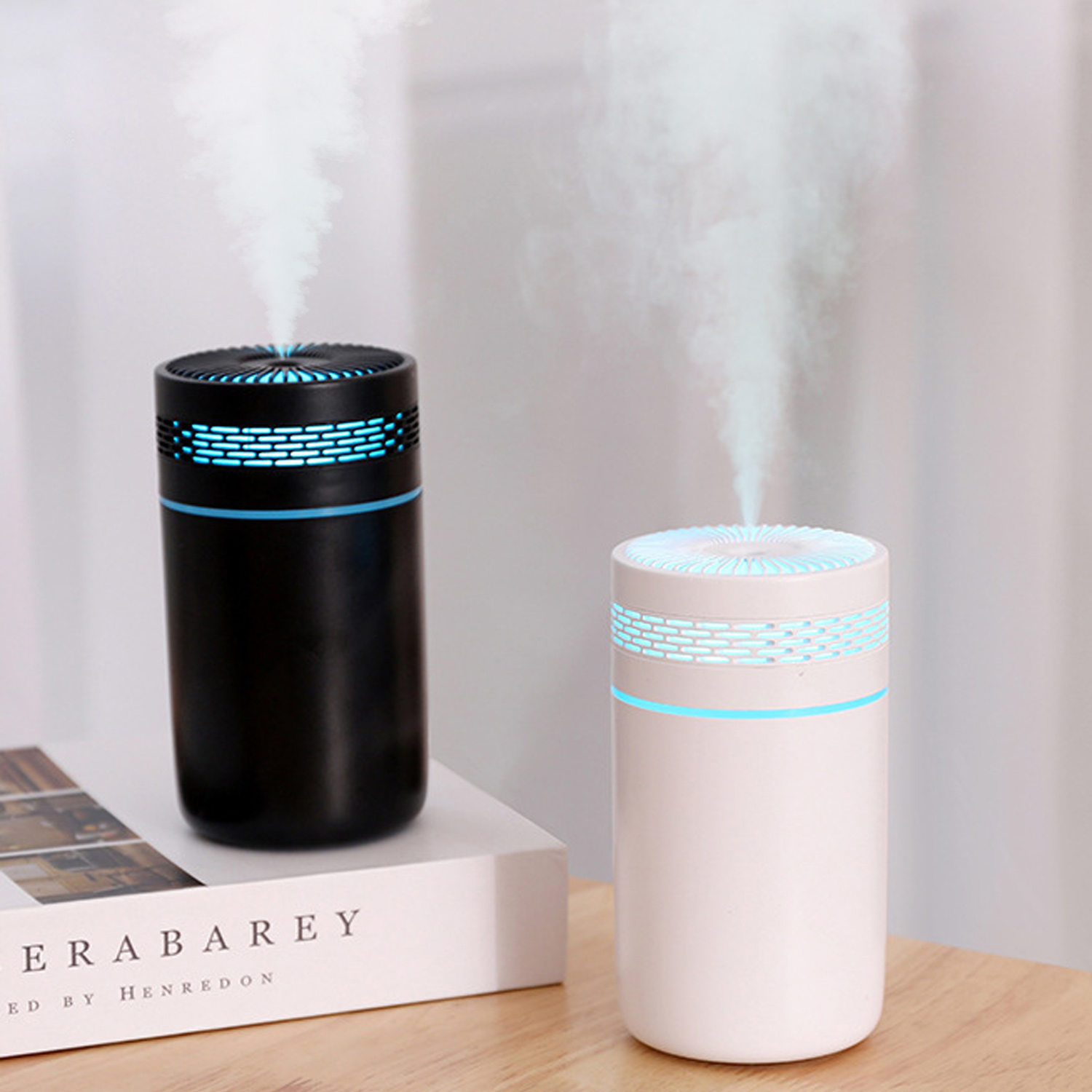 Dwa cylindryczne czarno-białe nawilżacze. Para unosi się z góry każdego z nich.