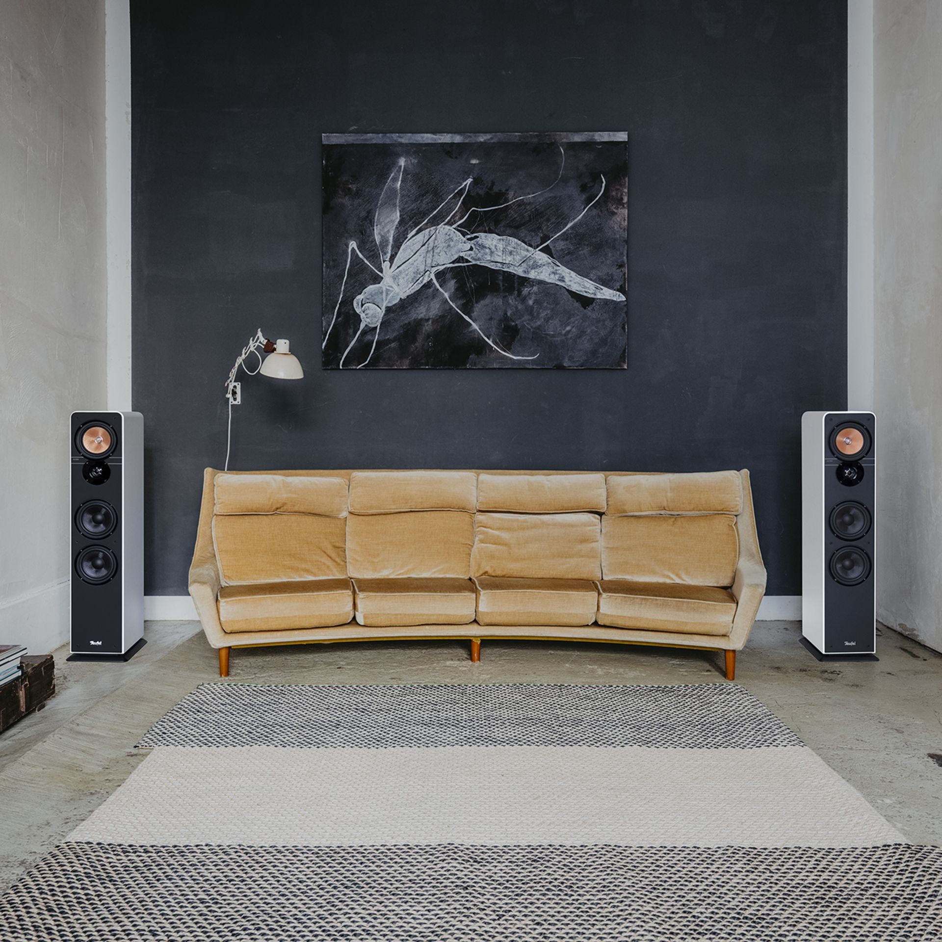 Raum mit Lautsprechern, Couch, Teppich und Gemälde.
