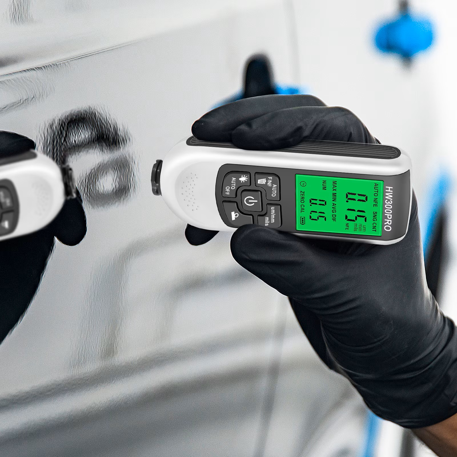 Eine Person in schwarzen Handschuhen verwendet ein digitales Lackschichtdickenmessgerät an einem Auto.