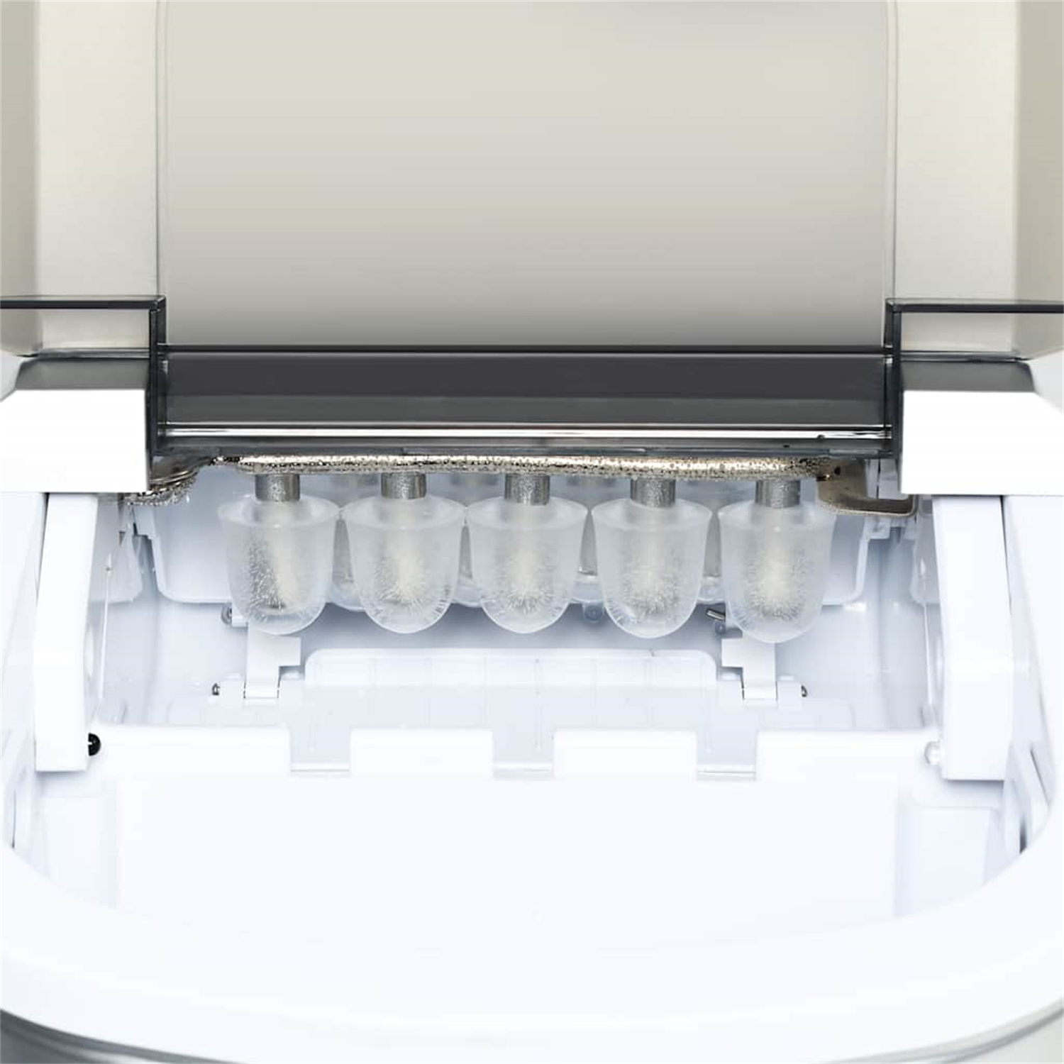 Im Inneren eines Eisbereiters, der die Eisformen zeigt. Klares Eis in Formen und eine Metallstange darüber.