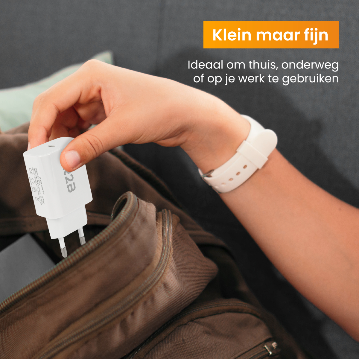 Eine Person hält einen weißen Netzadapter, mit einer Geldbörse im Hintergrund und Text auf Niederländisch.