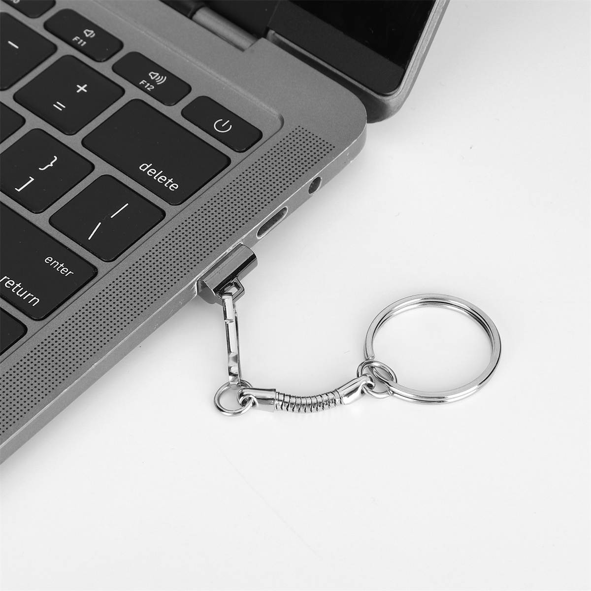 Ein silberner USB-Stick mit Schlüsselring, der an einen grauen Laptop angeschlossen ist.
