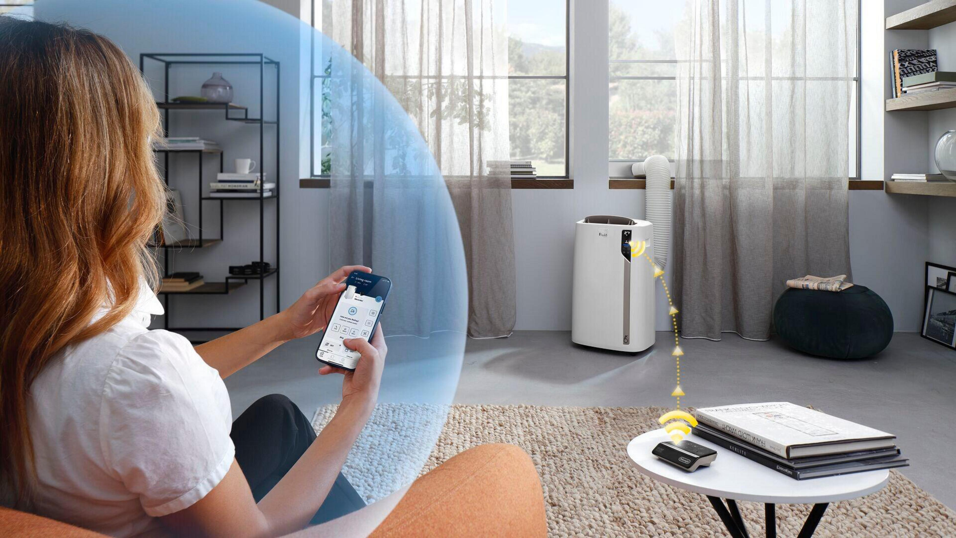 Una donna usa uno smartphone per controllare un condizionatore d'aria. L'unità AC è sullo sfondo.