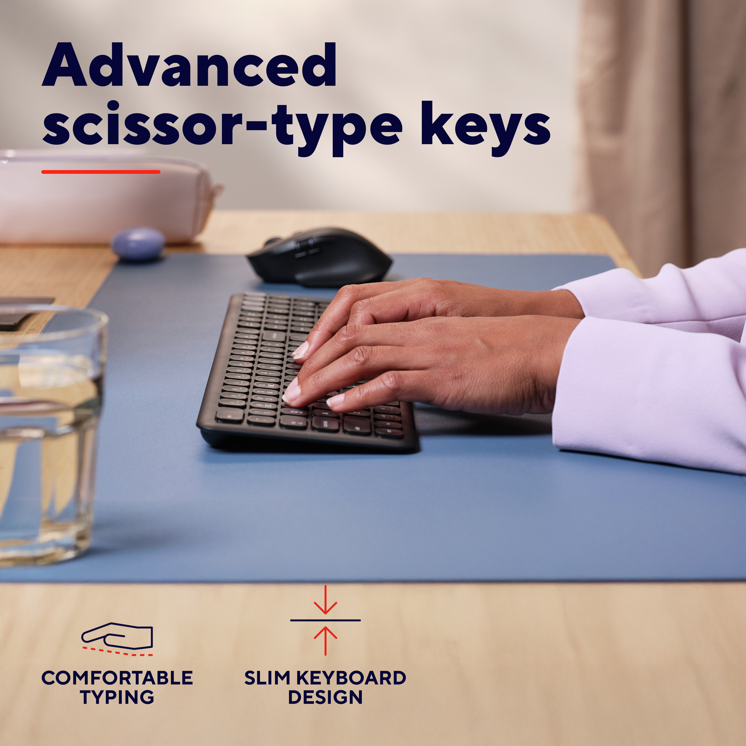 Ręce piszące na czarnej klawiaturze na niebieskiej macie, z myszą i szklanką wody.