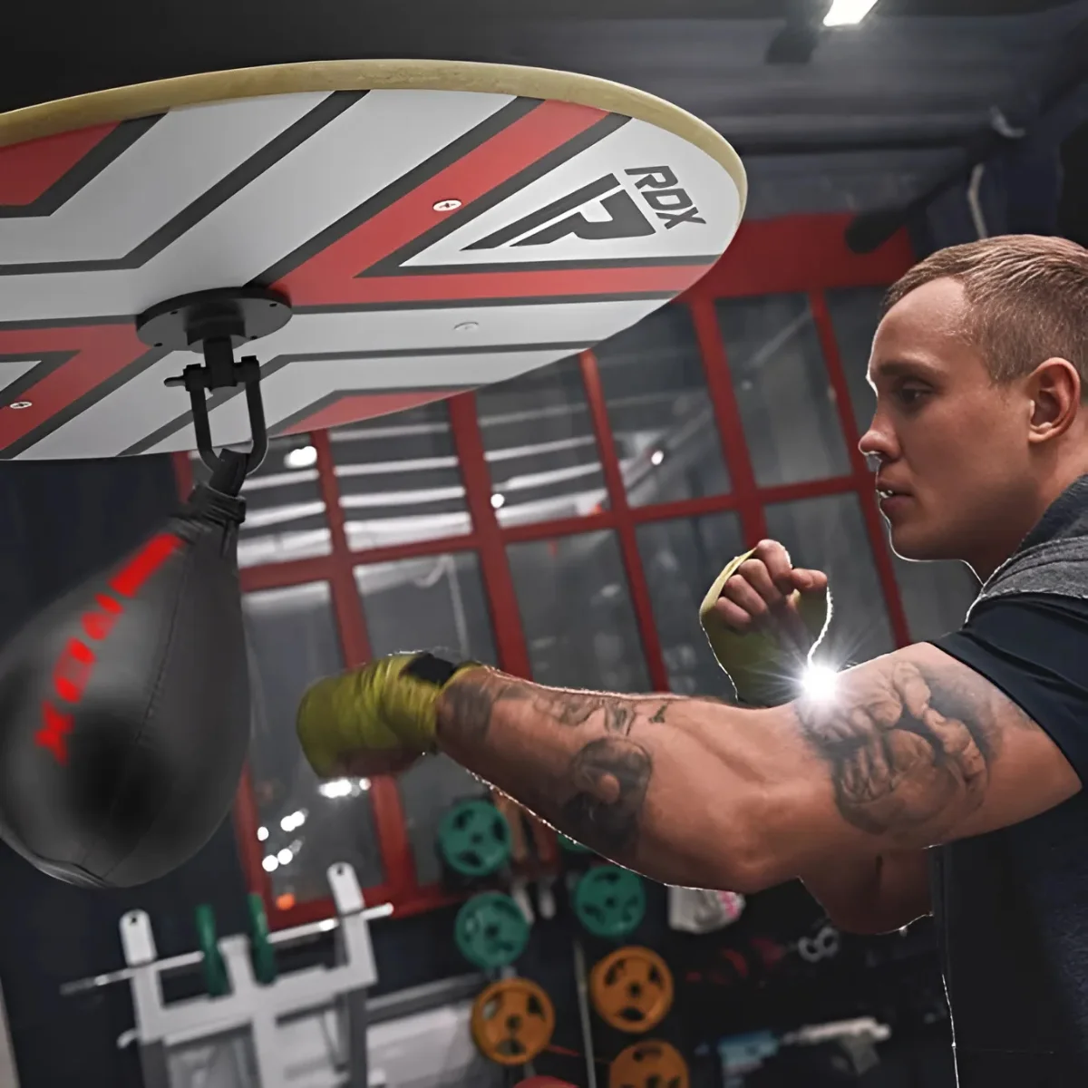 Man boxing with a speed bag. He's wearing wraps and a black speed bag is visible.