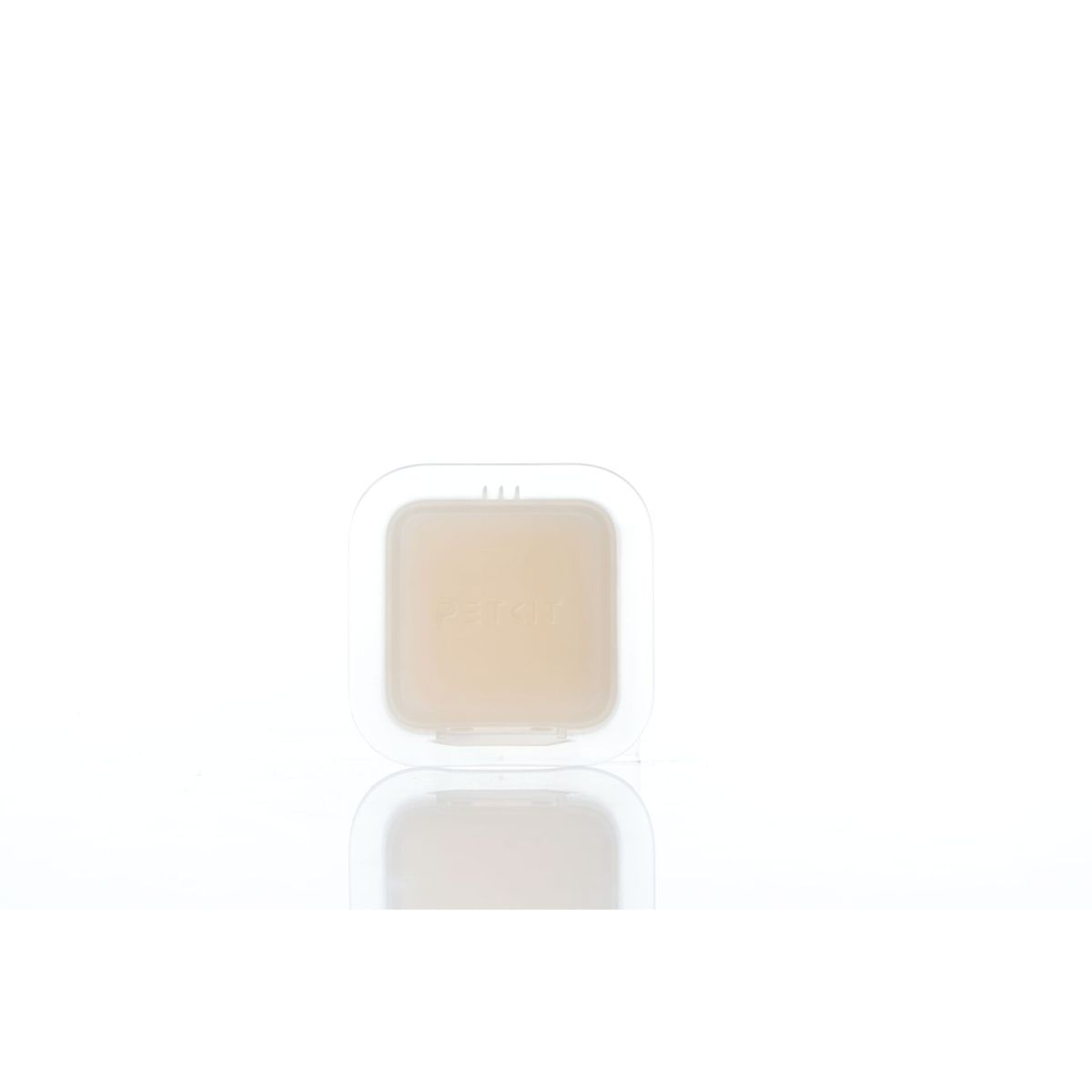 Ein kleiner, klarer Behälter mit einem beigefarbenen Pad darin. Der Behälter ist transparent. Weißer Hintergrund.