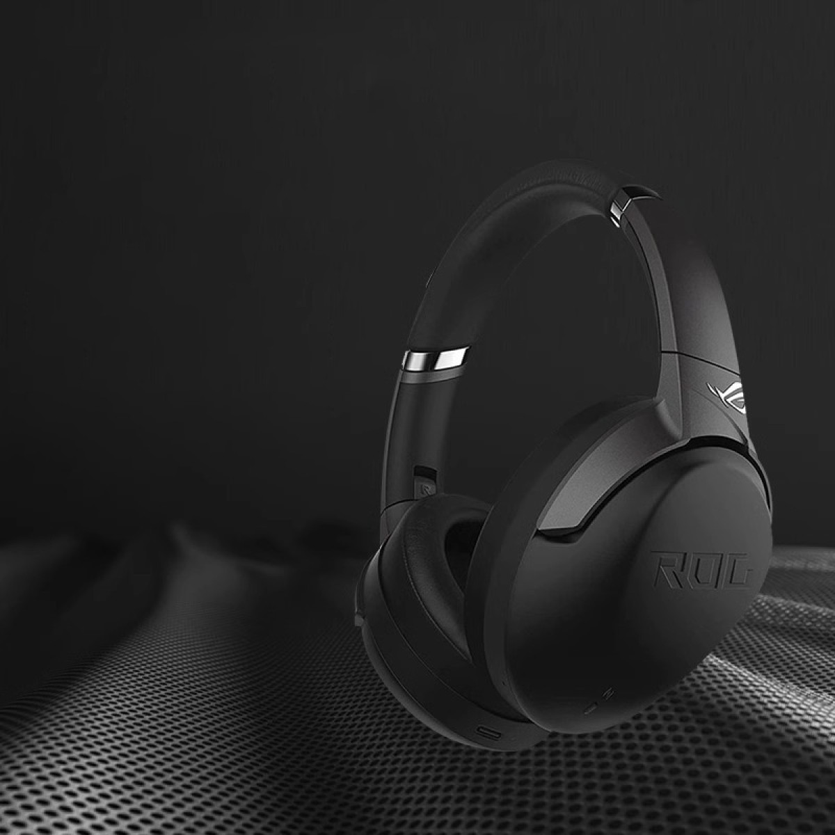 Czarne słuchawki dla graczy z logo ROG na ciemnej powierzchni.