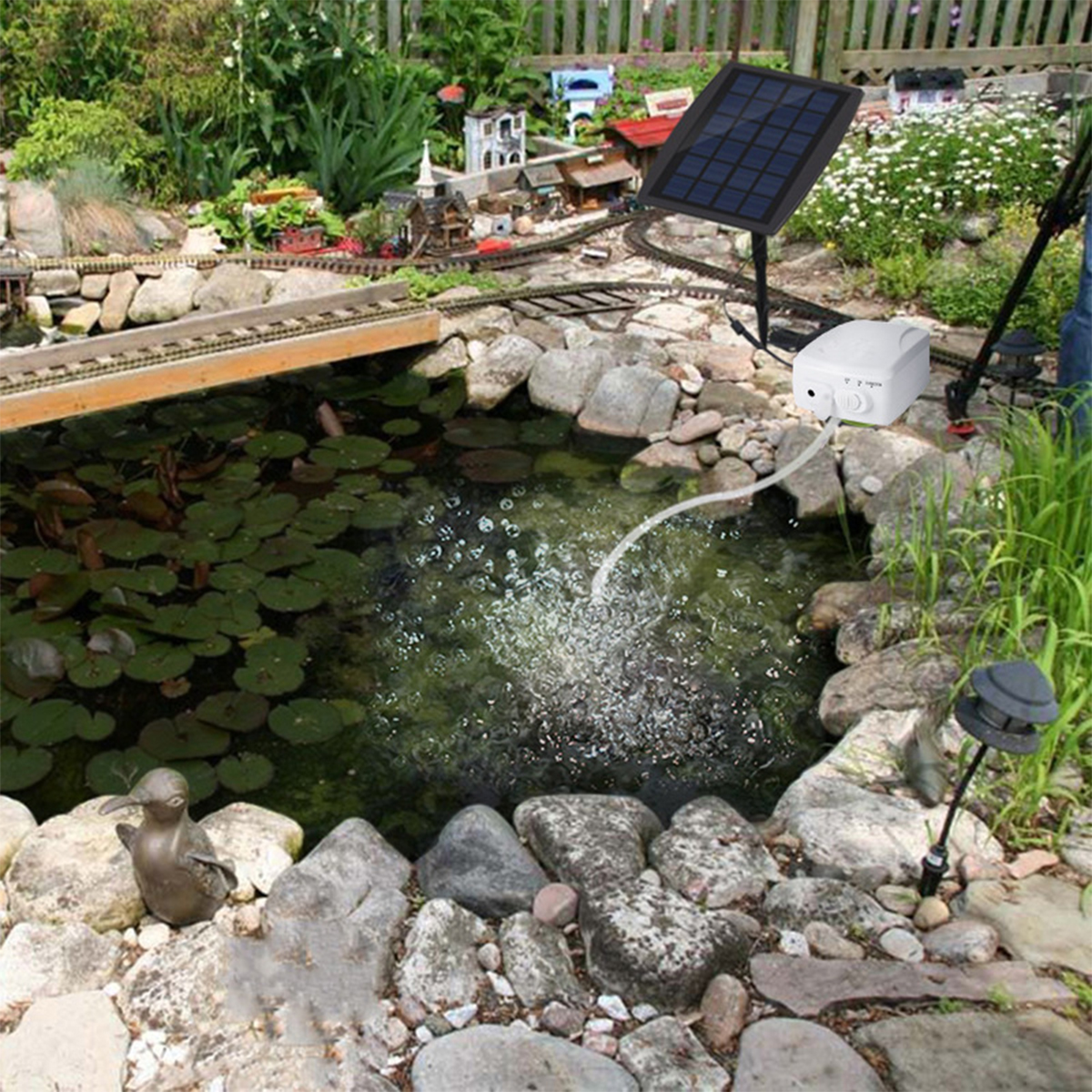 Ein Gartenteich mit Solarpanel, kleiner Bahngleis und Miniatur-Eisenbahn.