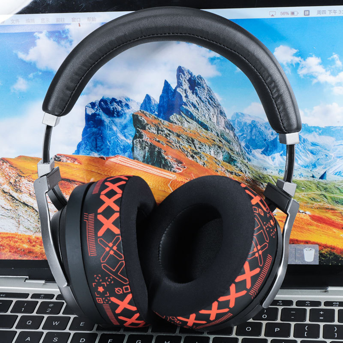 Słuchawki na laptopie, pokazujące górski krajobraz. Słuchawki są czarne i pomarańczowe.