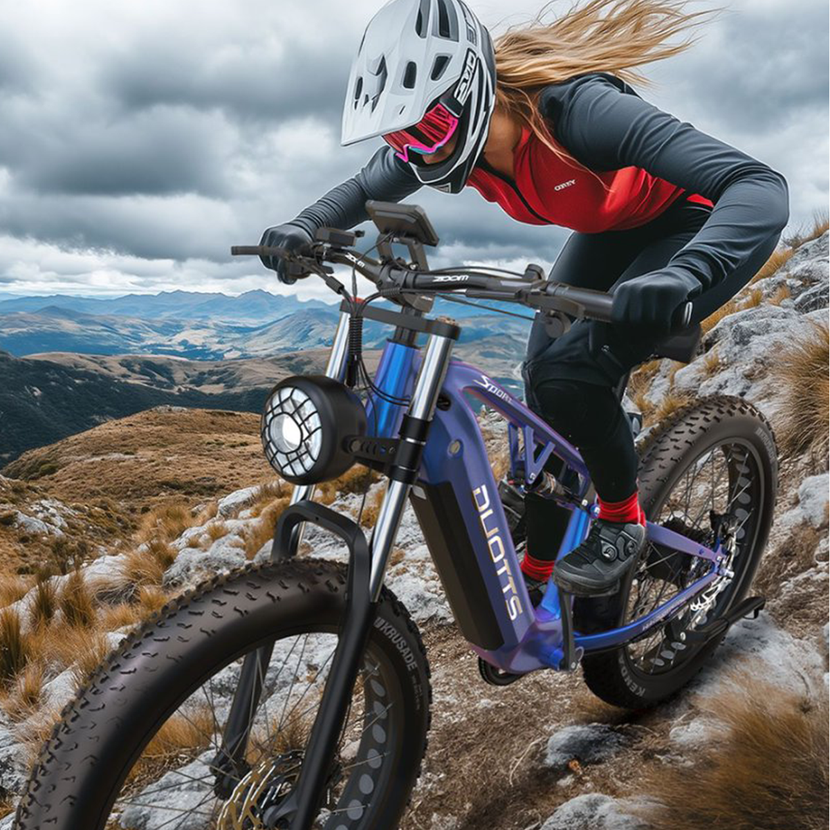 Eine Frau fährt mit einem blauen Mountainbike auf einem felsigen Bergpfad. Das Fahrrad hat einen Scheinwerfer.