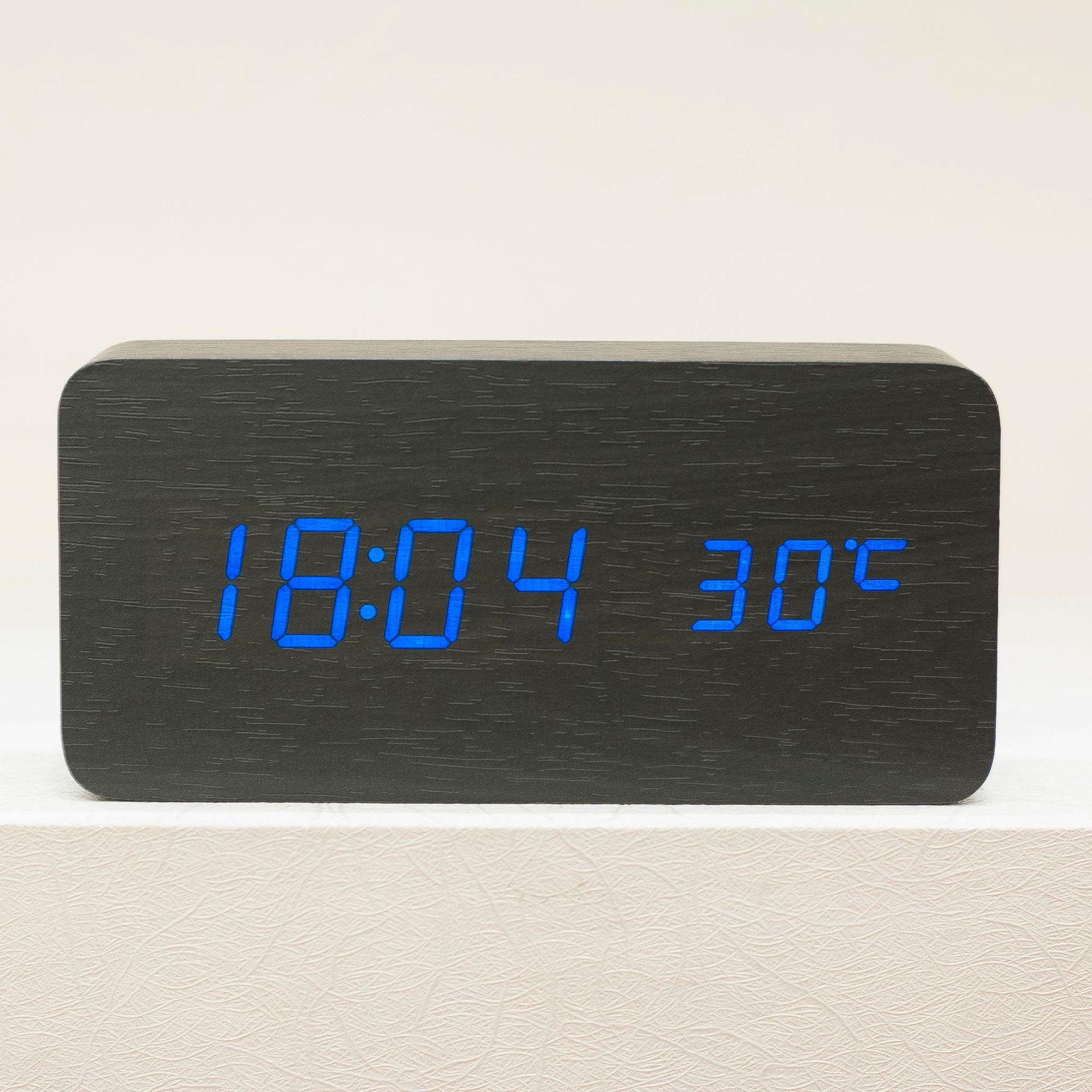 Black wooden digital alarm clock displaying the time and temperature in blue digits.