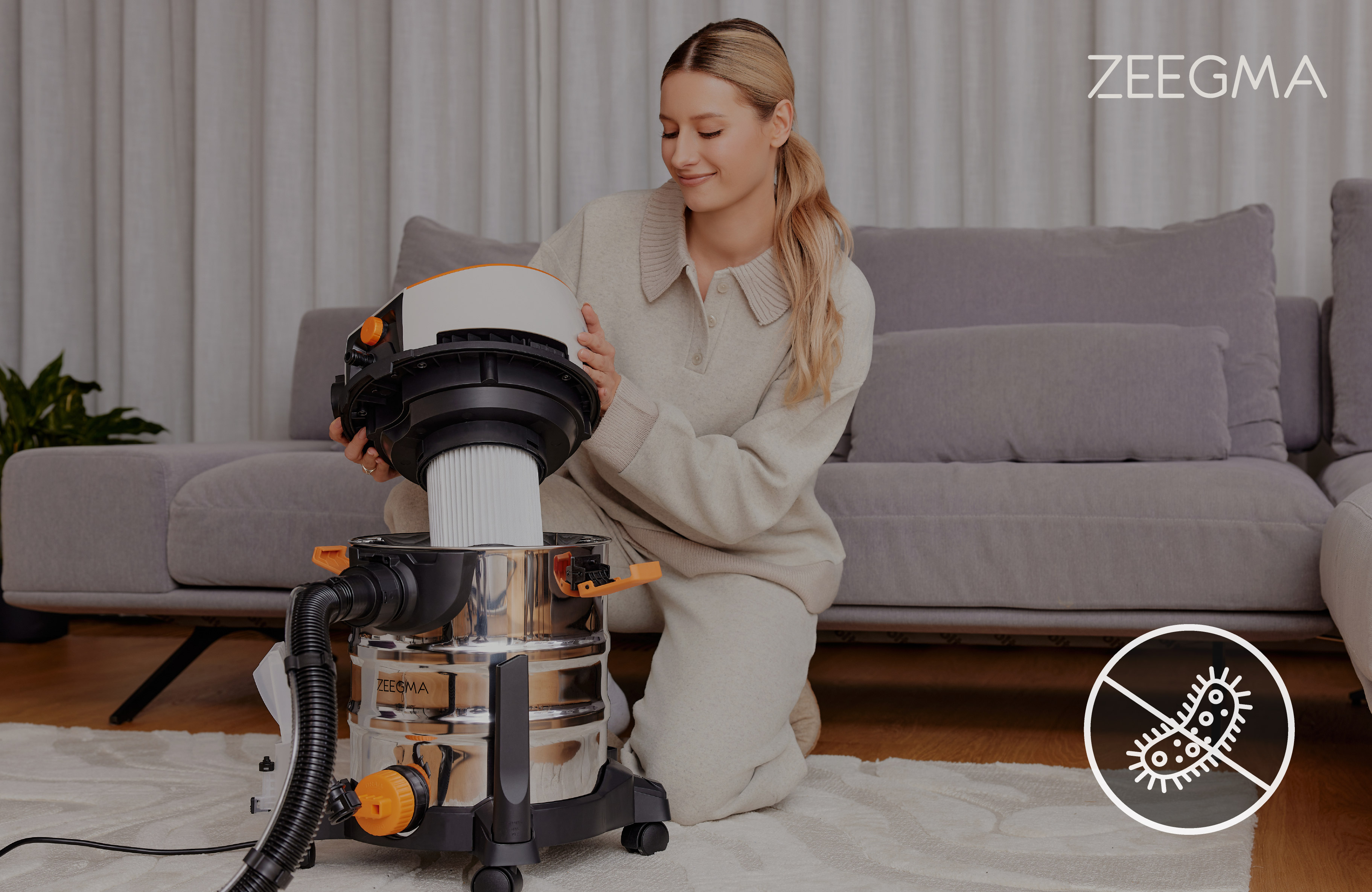 Kobieta składająca odkurzacz obok sofy, z ikoną antybakteryjną.