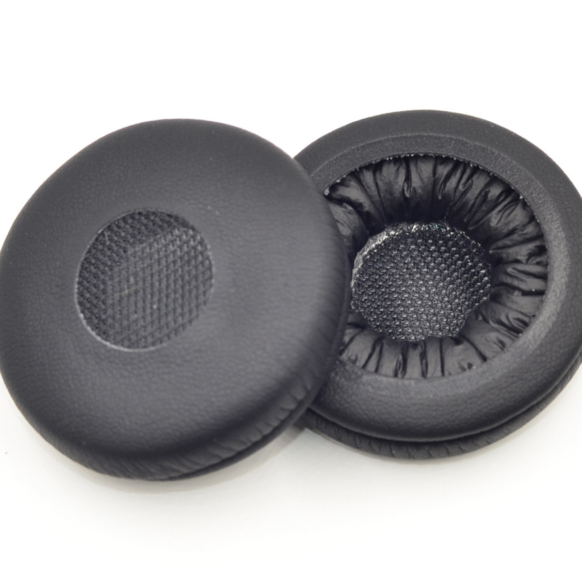 Dwie czarne nauszniki do słuchawek, wykonane z miękkiego, wyściełanego materiału, na białej powierzchni.