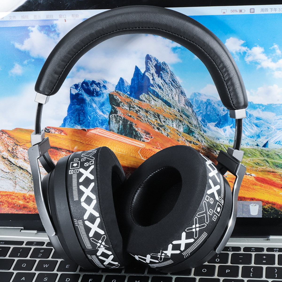 Czarne słuchawki na klawiaturze z obrazem gór na ekranie.