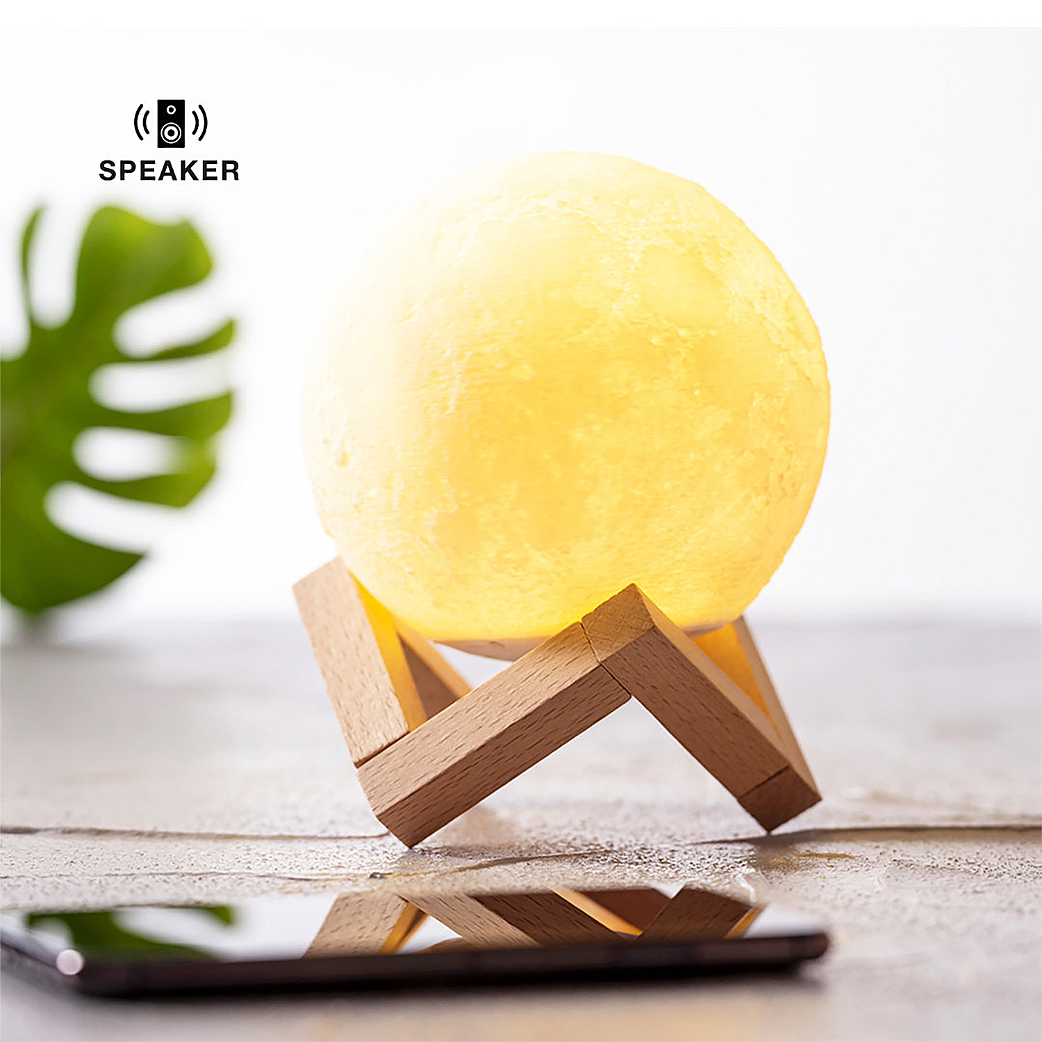 Lampada a forma di luna su un supporto in legno. È illuminata, un telefono in primo piano.