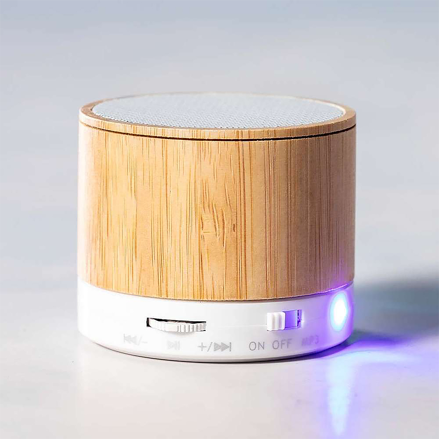 Piccolo altoparlante in legno con controlli e luce blu brillante.