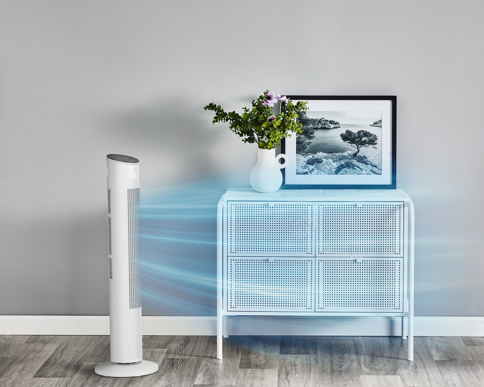 Biały wentylator, biała szafka i ramka na zdjęcia.