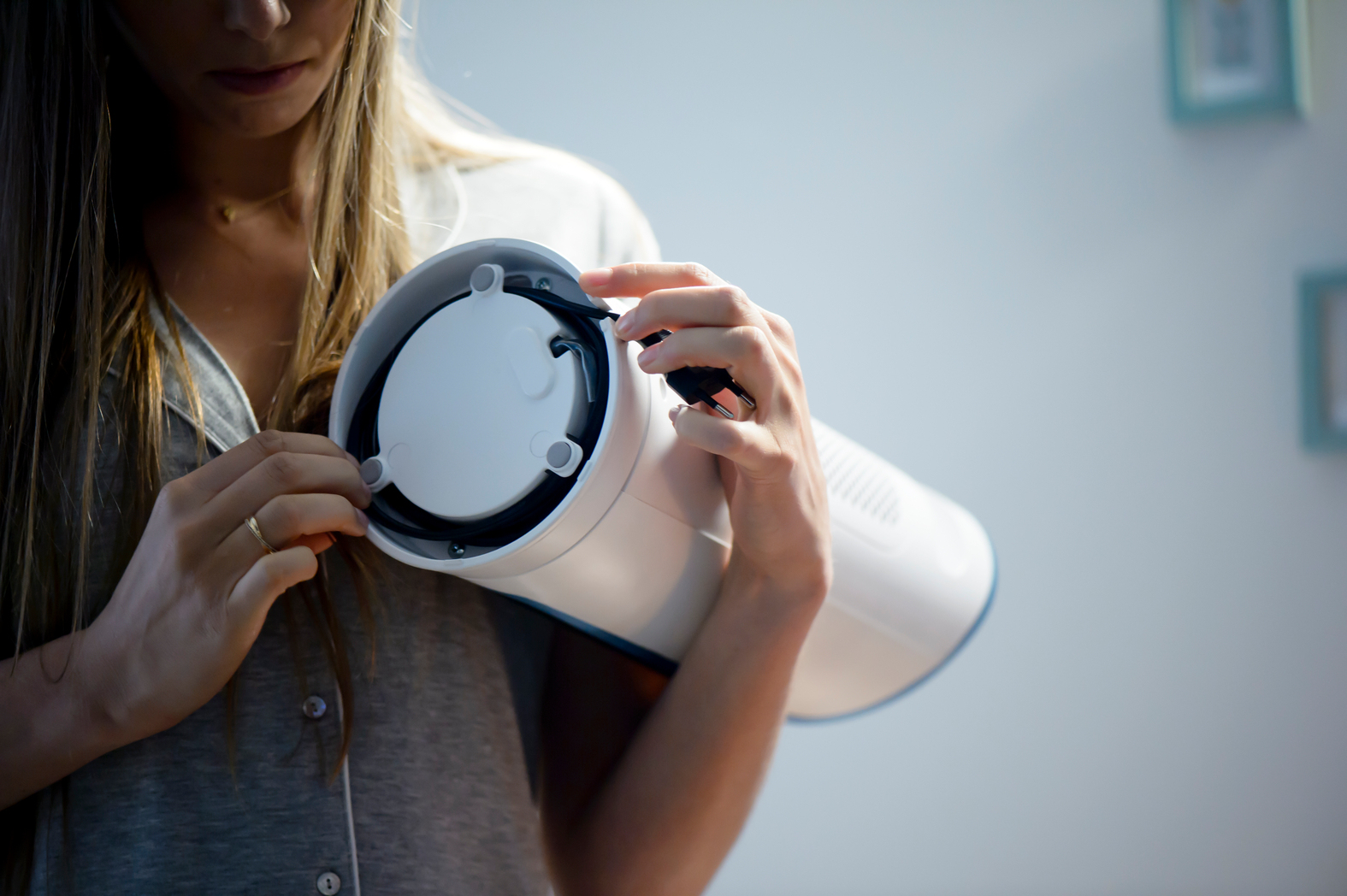 Kobieta trzyma biały element wentylatora. Przygotowuje się do montażu.