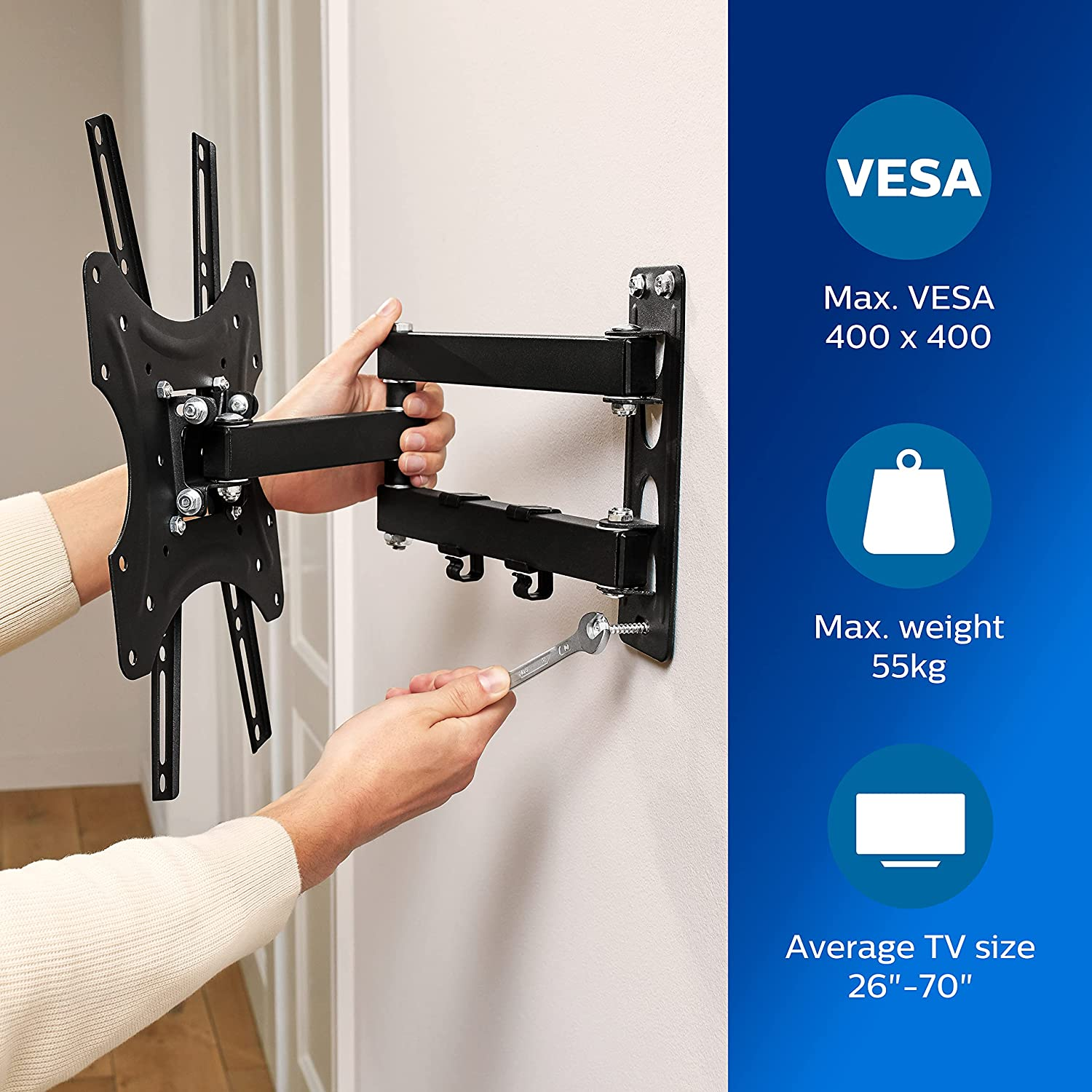 Eine Person montiert mit einem Schraubenschlüssel eine schwarze TV-Halterung an einer Wand.