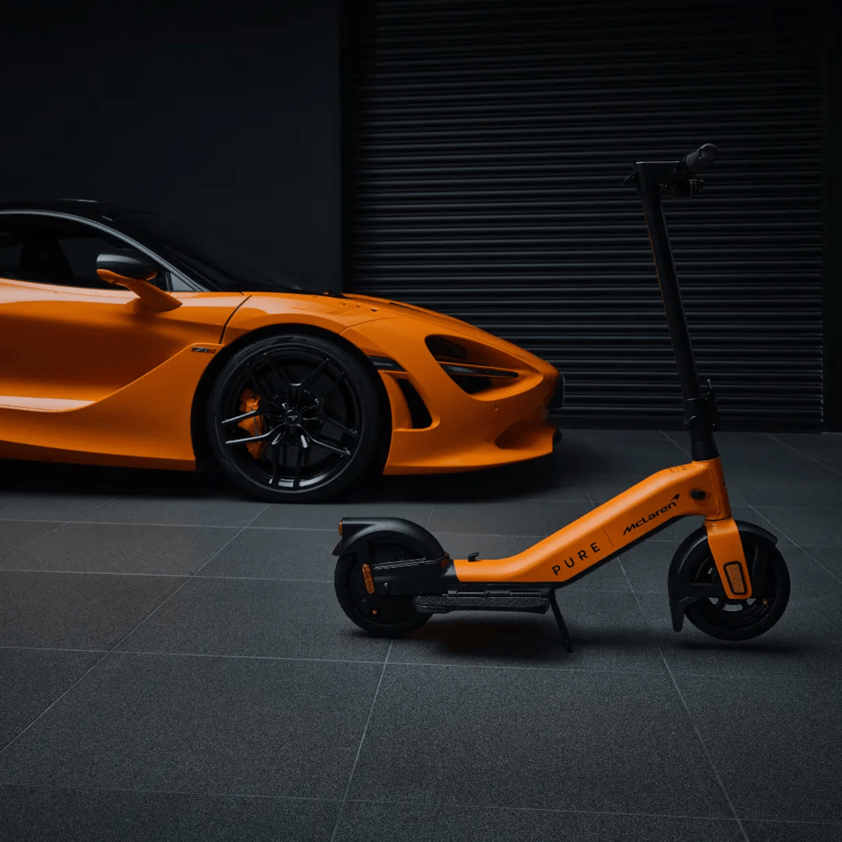 Oranger McLaren-Wagen und -Roller parken auf grauem Fliesenboden, dunkler Hintergrund.
