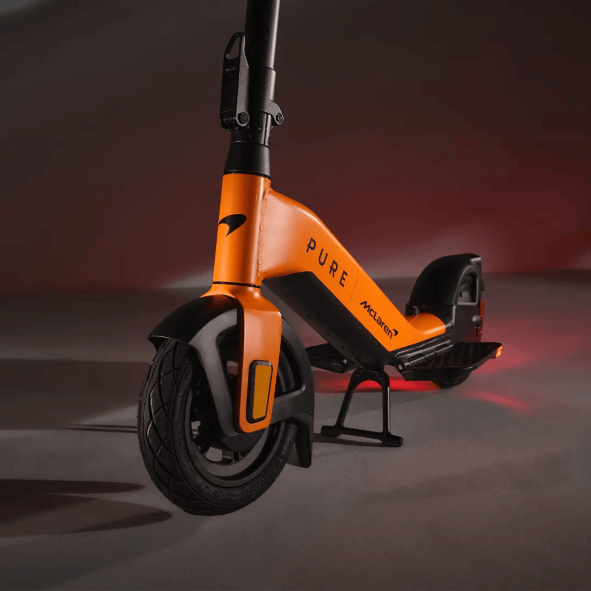 Oranger und schwarzer McLaren-Roller auf dunkler Oberfläche mit roter Beleuchtung.