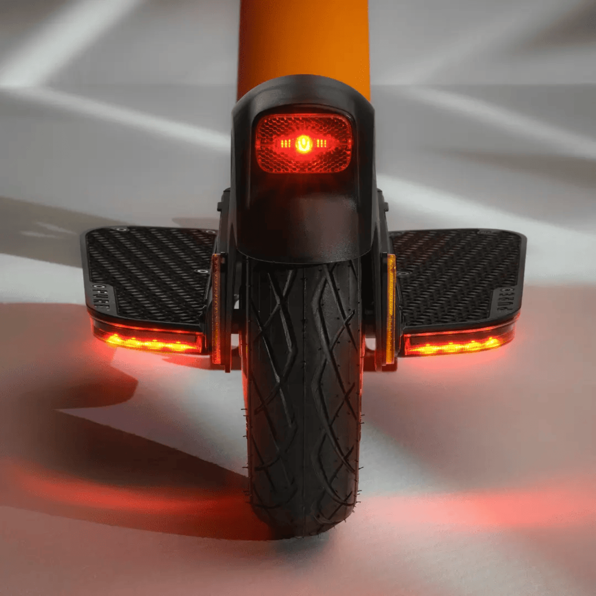 Rückansicht eines schwarz-orangenen elektrischen Einrads mit roten Lichtern, die das Rad und die Rückseite beleuchten.