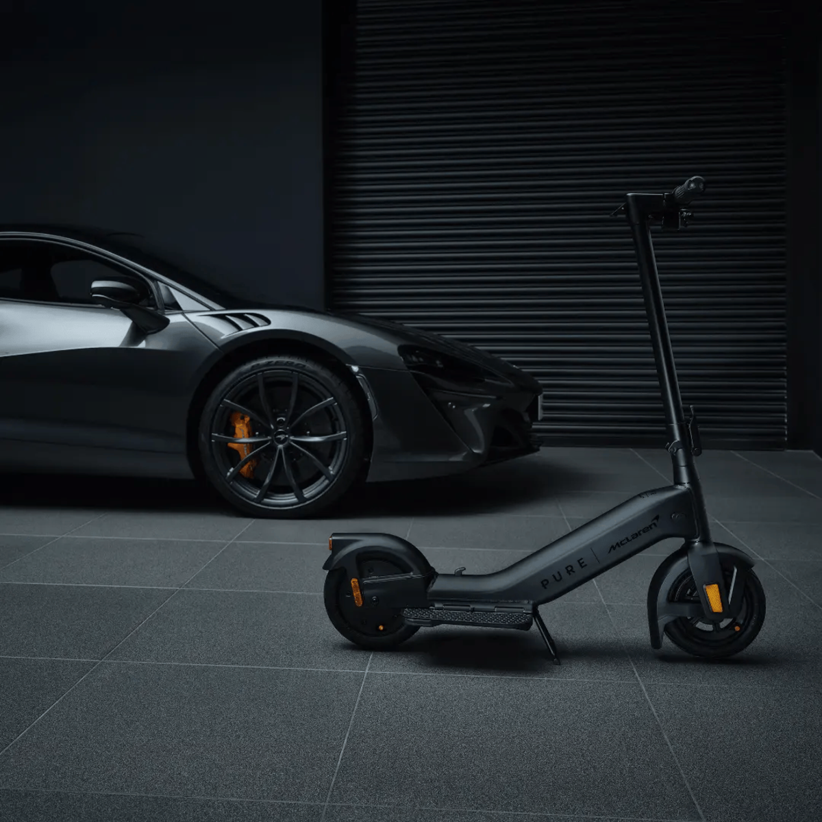 Ein schwarzer Elektroroller und ein grauer Sportwagen in einer dunklen Garage.