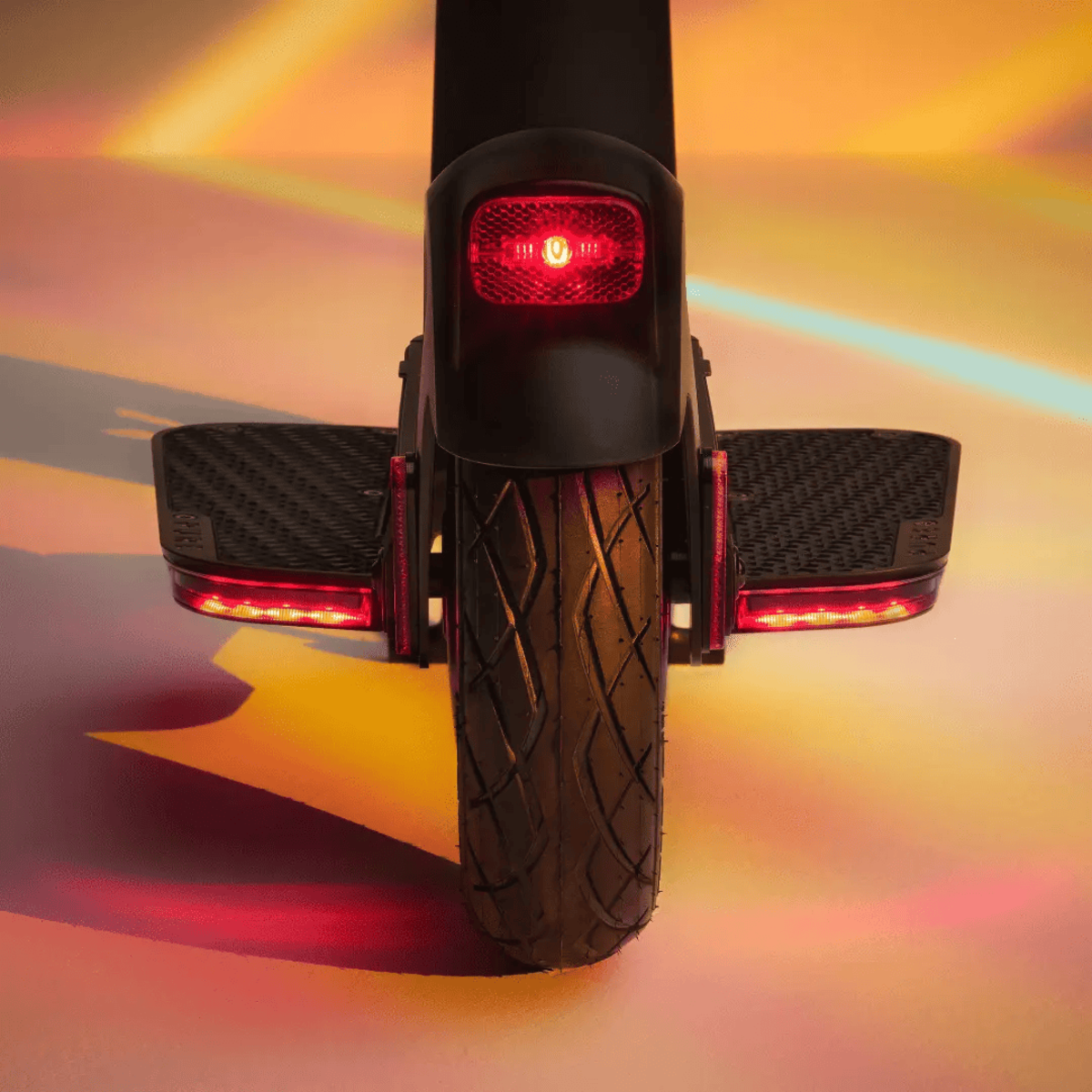 Rückansicht eines Elektrorollers. Rote Lichter sind am Rad und hinten eingeschaltet.