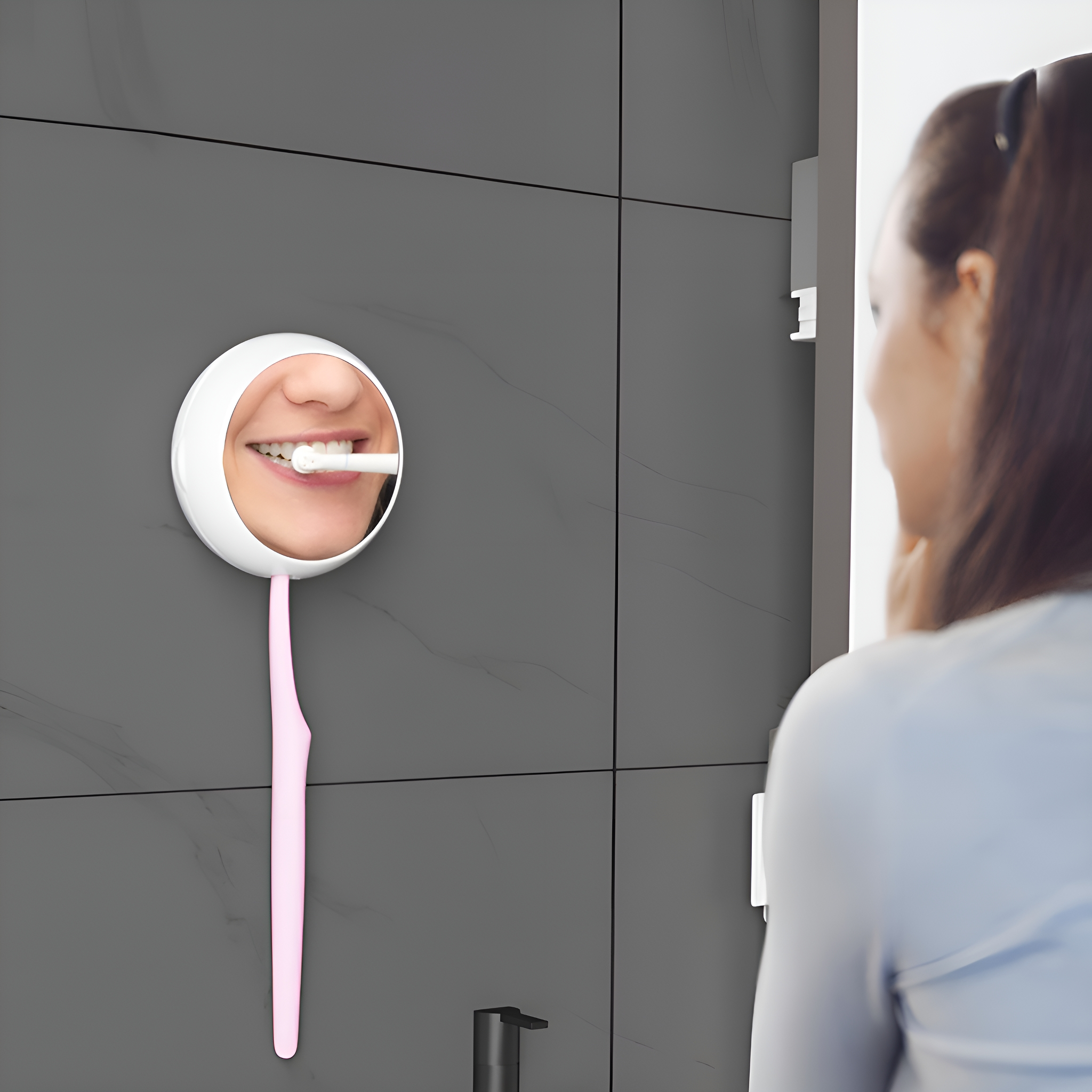 Eine Frau putzt sich im Spiegel die Zähne. Eine rosa Zahnbürste ist an einem Spiegel an einer grauen Wand befestigt.